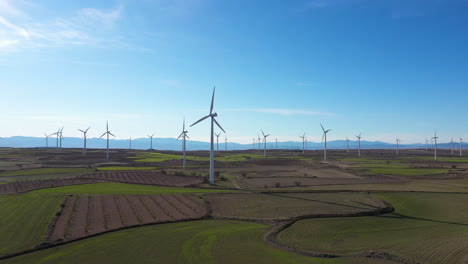 Turbinas-Eólicas-En-Un-Campo-Verde-Viñedos-Cielo-Azul-Toma-Aérea-España